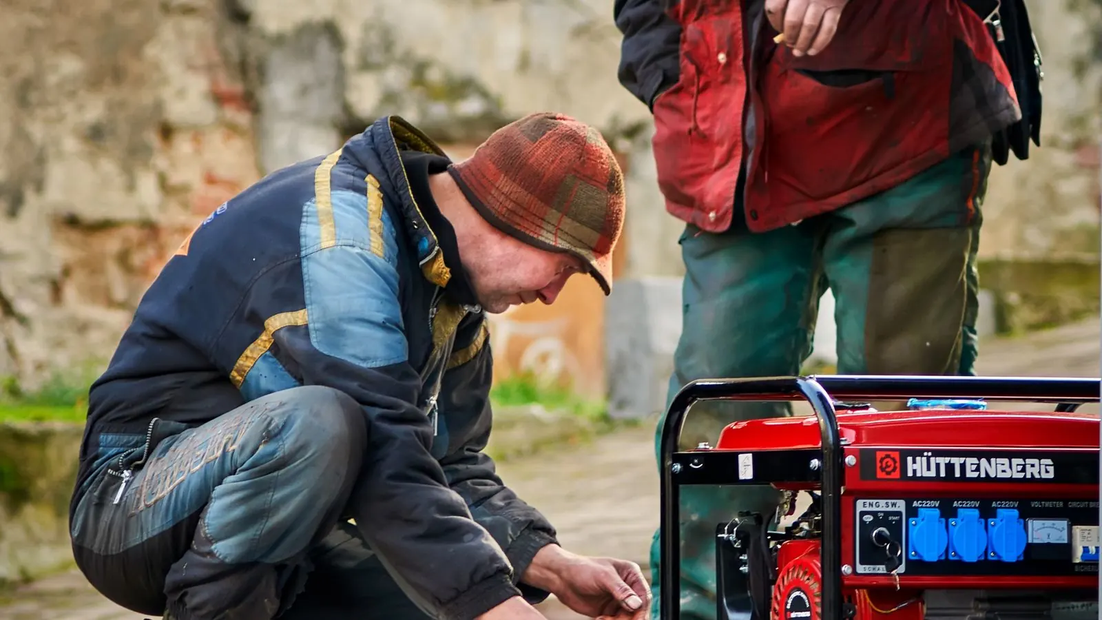 Two technicians setting up a red portable generator outdoors