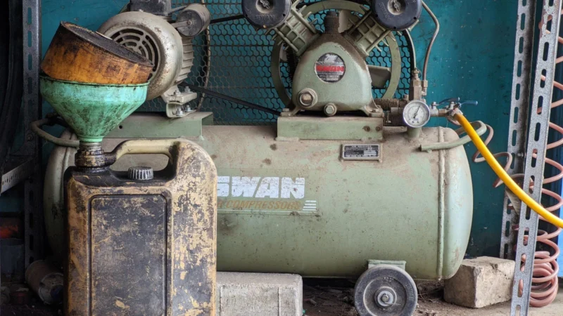 Older vertical-tank air compressor in a workshop