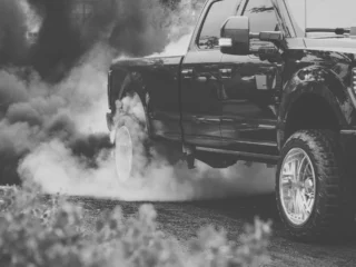 Black pickup truck emitting thick exhaust smoke