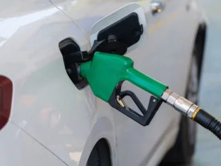 Green fuel nozzle refueling a white vehicle