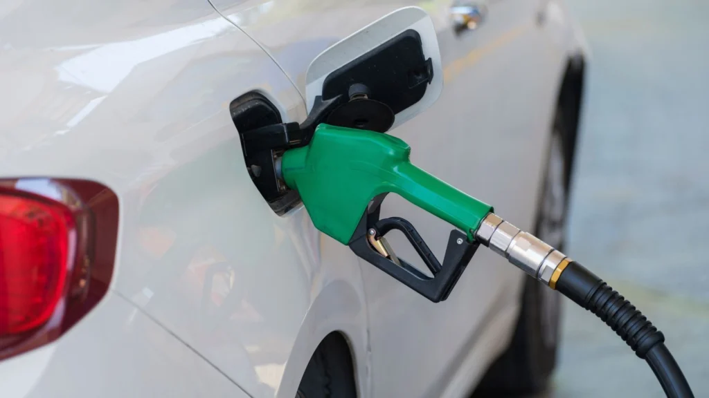 Green fuel nozzle refueling a white vehicle