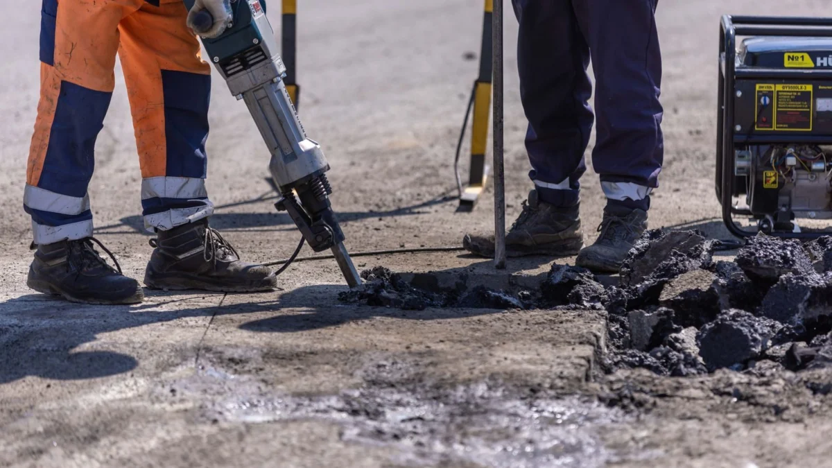 Construction workers using a jackhammer powered by a portable generator