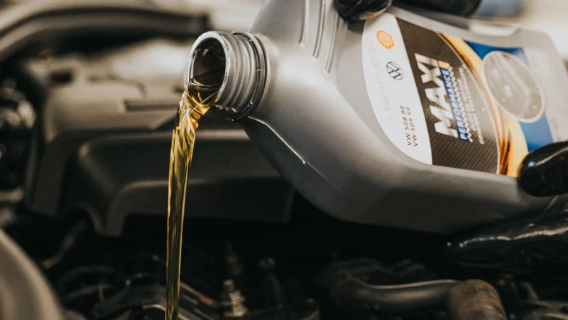 Gloved hand pouring engine oil into an engine