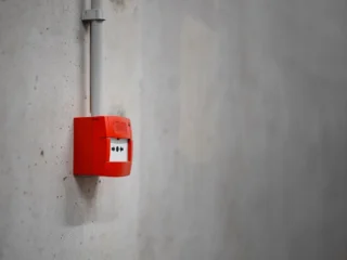 Red alarm unit mounted on a gray concrete wall
