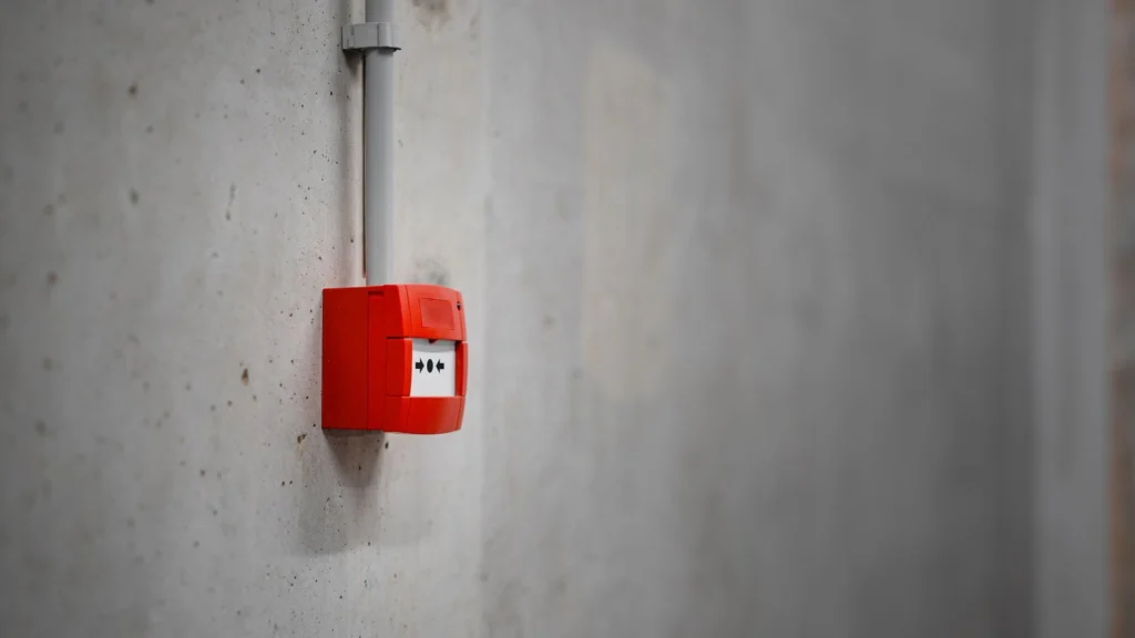 Red alarm unit mounted on a gray concrete wall