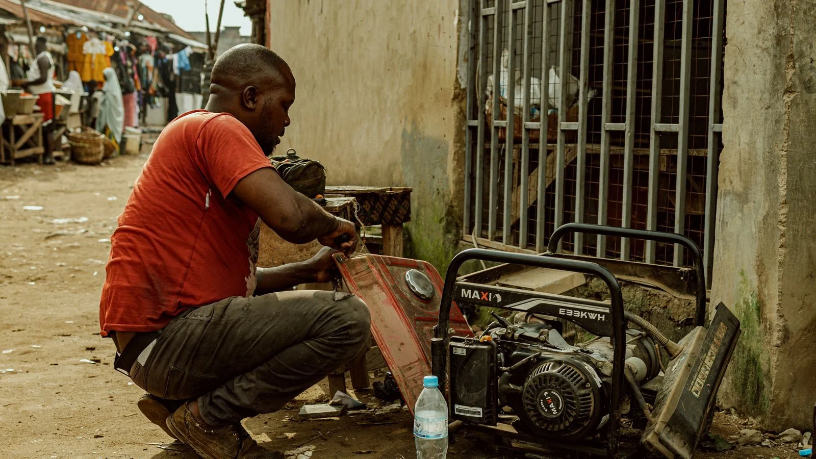 Man in a red shirt repairing a portable generator