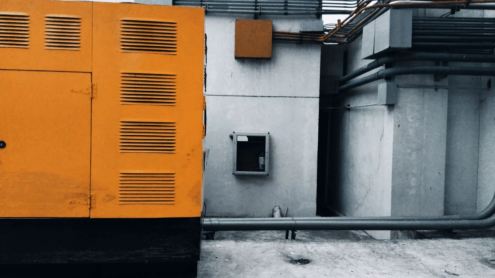Orange enclosed generator set installed outside a building
