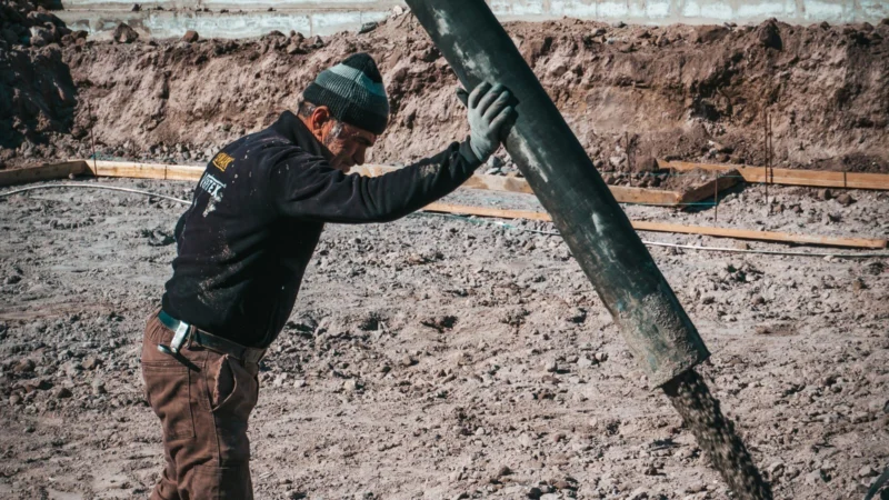 Worker guiding a pump hose on a construction site