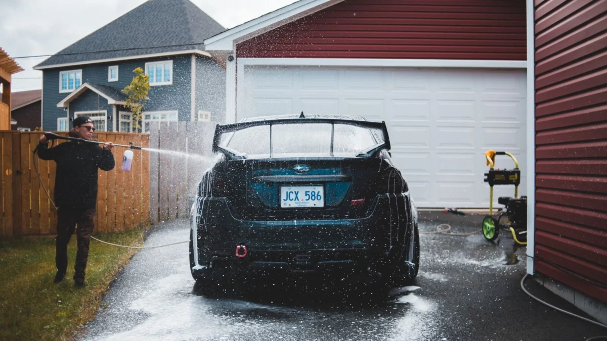 Man using a pressure washer wand on a driveway